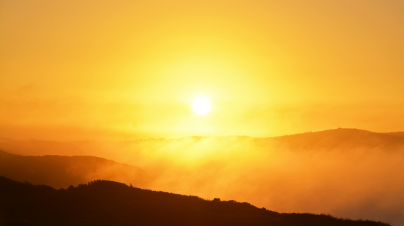 Soleil levant sur une chaîne de montagnes avec de la brume